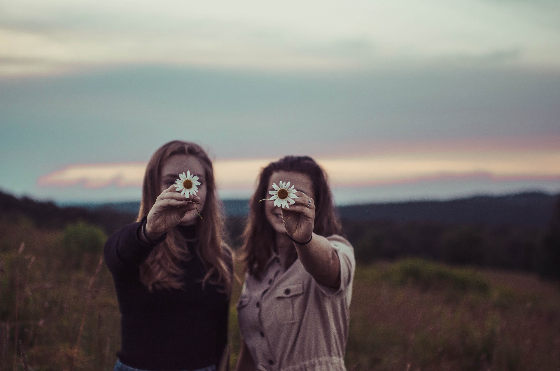 two young women with flowers in front of their face; metaphor for understanding Instagram benchmarks and easy goal setting